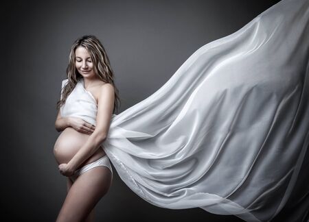 Portrait of a pregnant woman wrapped in cloth looking downの写真素材
