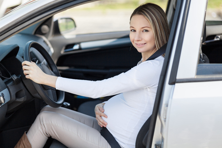 Pregnant woman driving her car, wearing seat beltの写真素材