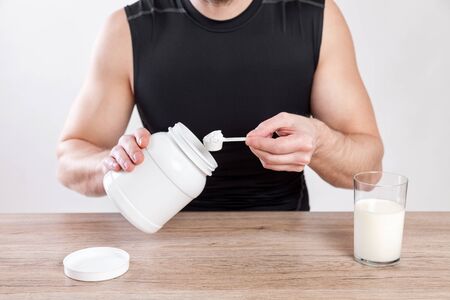 Closeup on a man with nutiotion and protein supplements on tableの写真素材