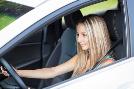 Young woman behind the steering wheel concentrates on drivingの写真素材