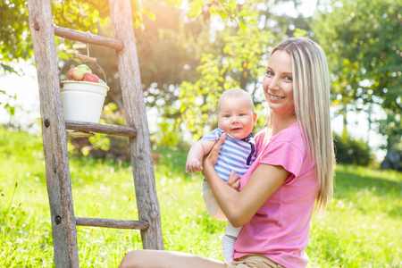 Mother with her baby picking apples from an apple treeの写真素材