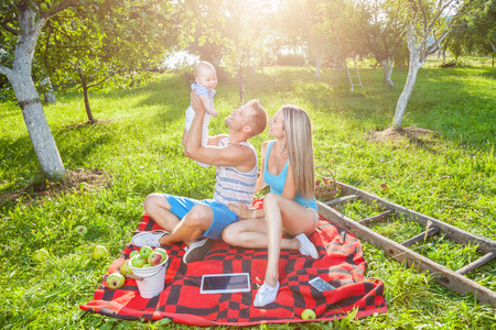 Happy family enjoying a picnic with their baby outdoorsの写真素材