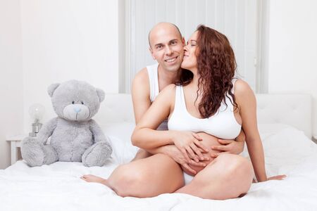 Delighted young parents in bed expecting a little babyの写真素材