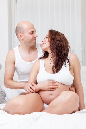 Delighted young parents in bed expecting a little babyの写真素材