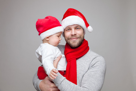 Father with his baby boy wearing Santa hats celebrating Christmasの写真素材