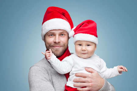 Father with his baby boy wearing Santa hats celebrating Christmasの写真素材