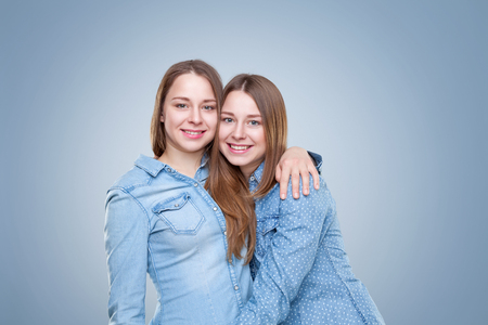 Studio portait of young and happy twin sisters embracingの写真素材