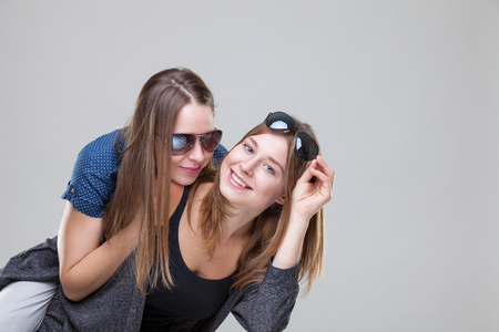 Studio portait of young and happy twin sisters embracingの写真素材
