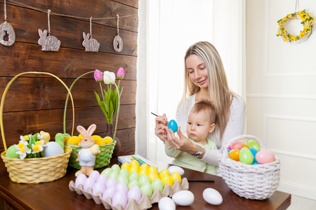 Easter concept. Happy mother and her cute child getting ready for Easter by painting the eggsの写真素材