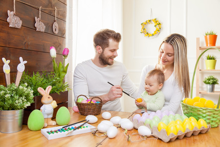 Easter concept. Happy and loving mother and father preparing home decoration with their child for Easter holidaysの写真素材