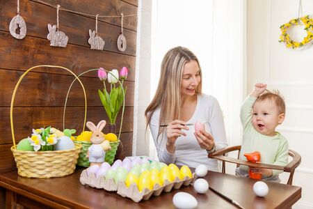 Easter concept. Happy mother and her cute child getting ready for Easter by painting the eggsの写真素材