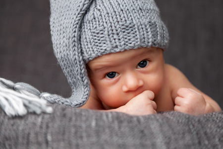 Beautiful newborn baby wearing a cute grey hatの写真素材