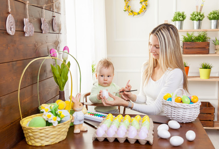 Easter concept. Happy mother and her cute child getting ready for Easter by painting the eggsの写真素材
