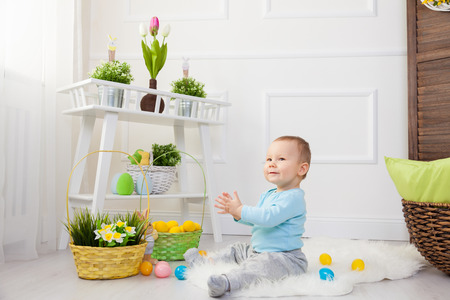 Easter egg hunt. Adorable child playing with colorful Easter eggs at homeの写真素材