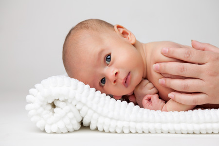 Cute newborn baby lying on a white blanketの写真素材