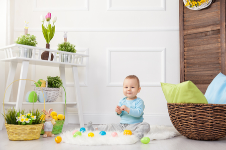 Easter egg hunt. Adorable child playing with colorful Easter eggs at homeの写真素材