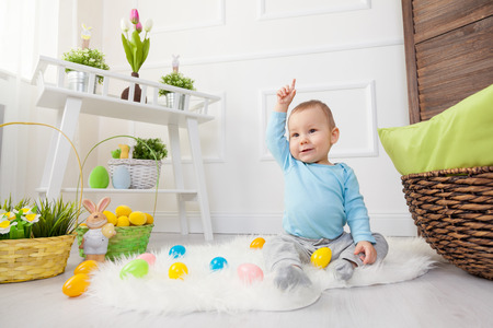 Easter egg hunt. Adorable child playing with colorful Easter eggs at homeの写真素材