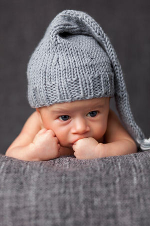 Beautiful newborn baby wearing a cute grey hatの写真素材