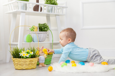 Easter egg hunt. Adorable child playing with colorful Easter eggs at homeの写真素材