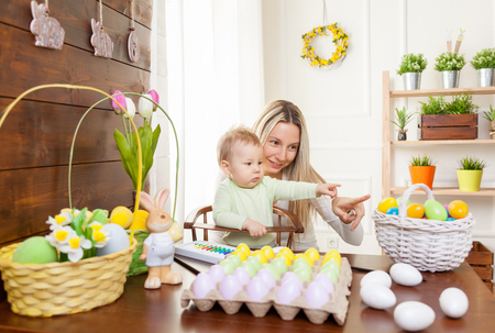Easter concept. Happy mother and her cute child getting ready for Easter by painting the eggsの写真素材