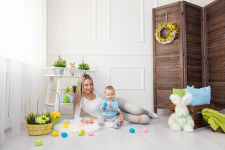 Delighted mother and her little child enjoying the Easter egg hunt at homeの写真素材