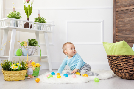 Easter egg hunt. Adorable child playing with colorful Easter eggs at homeの写真素材