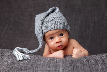 Beautiful newborn baby wearing a cute grey hatの写真素材