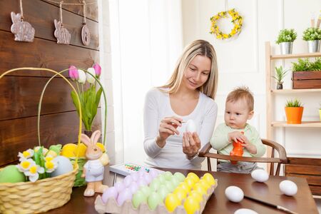 Easter concept. Happy mother and her cute child getting ready for Easter by painting the eggsの写真素材