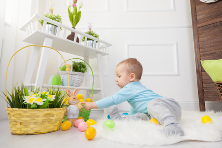 Easter egg hunt. Adorable child playing with colorful Easter eggs at homeの写真素材