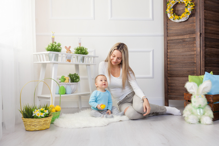 Delighted mother and her little child enjoying the Easter egg hunt at homeの写真素材