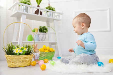 Easter egg hunt. Adorable child playing with colorful Easter eggs at home