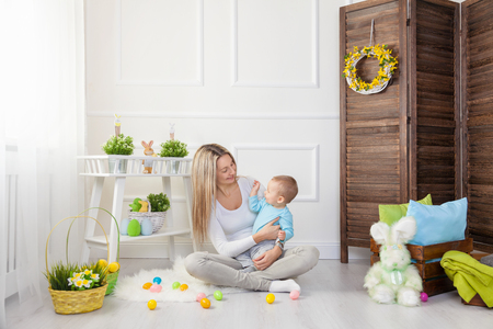 Delighted mother and her little child enjoying the Easter egg hunt at homeの写真素材