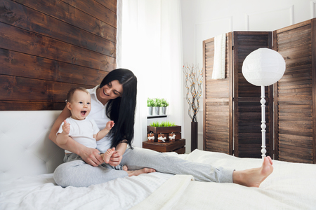 Happy mother with her cute little child on the bed having a good timeの写真素材