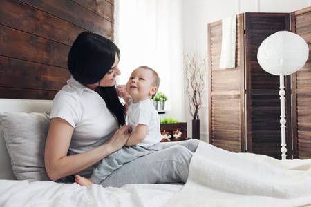 Happy mother with her cute little child on the bed having a good timeの写真素材