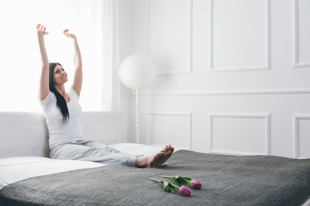 Beautiful young woman relaxing on the bed in the morningの写真素材
