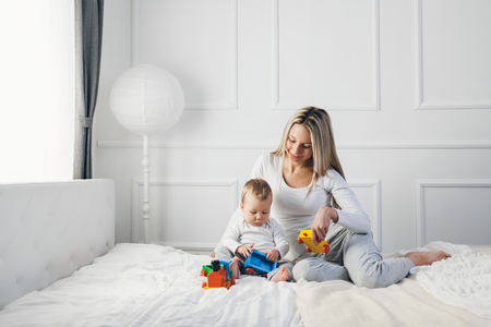 Happy mother with her cute little child on the bed having a good timeの写真素材