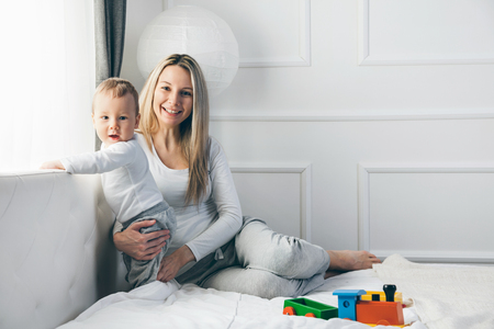 Happy mother with her cute little child on the bed having a good timeの写真素材