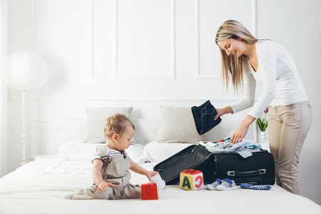 Travelling with kids. Happy mother with her child packing clothes for their holidayの写真素材
