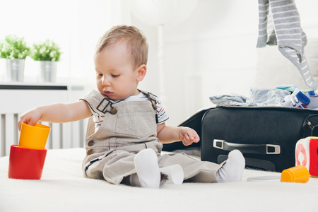 Travelling with kids. Cute toddler packing his clothes and toys for holidayの写真素材