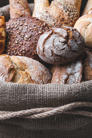 Delicious freshly baked bread inside a sack on wooden background