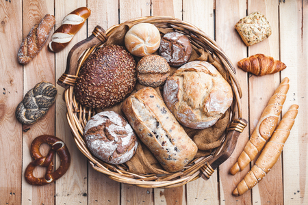 A basket full of delicious freshly baked bread on wooden backgroundの写真素材