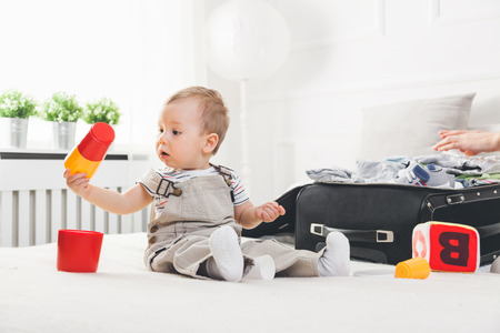 Travelling with kids. Cute toddler packing his clothes and toys for holidayの写真素材