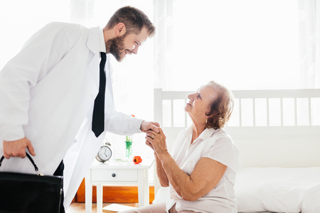 Providing care and support for elderly. Doctor visiting elderly patient at home.の写真素材