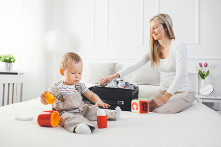 Travelling with kids. Happy mother with her child packing clothes for their holidayの写真素材