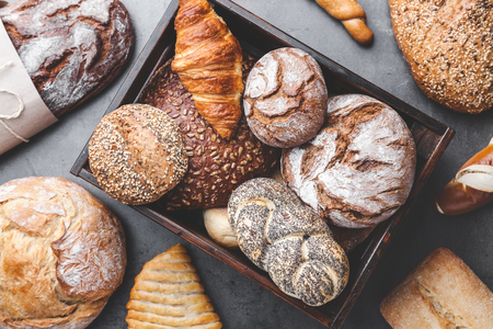 A basket full of delicious freshly baked bread on wooden backgroundの写真素材
