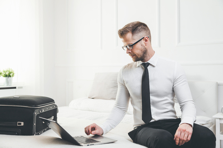 Young businessman working from a hotel room with his laptopの写真素材