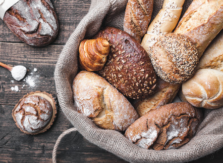 Delicious freshly baked bread inside a sack on wooden backgroundの写真素材