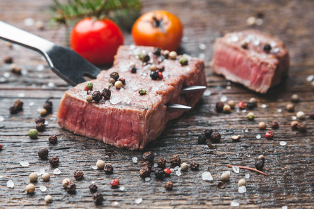 Delicious grilled beef steak with seasoning on wooden backgroundの写真素材