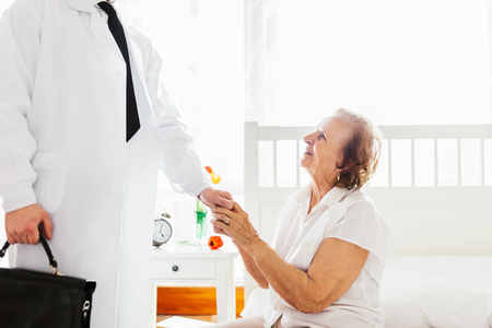 Providing care and support for elderly. Doctor visiting elderly patient at home.の写真素材