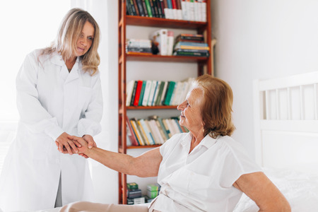 Providing care and support for elderly. Doctor visiting elderly patient at home.の写真素材